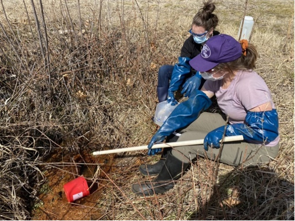 Figure 2: Elli Castonguay (undergraduate) and Dr. Sarah Fischer (postdoctoral fellow) sampling the mine adit where groundwater upwells to a surface stream.