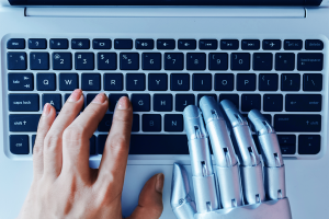 A computer keyboard with a human hand on the left and a robotic hand on the right.